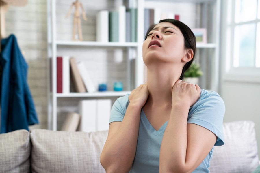 woman experiencing neck & shoulder pain on couch