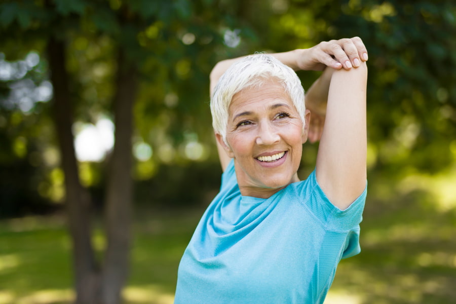 woman smiling and stretching her triceps
