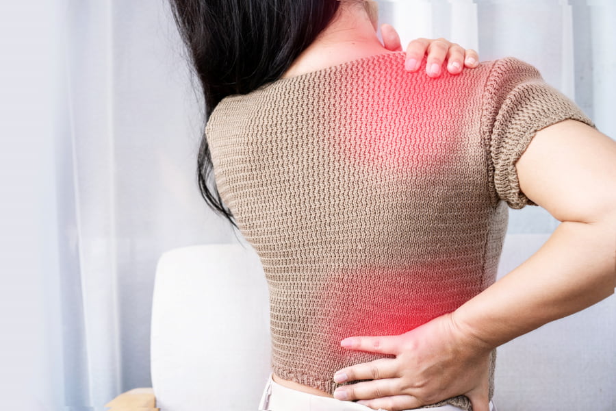 woman clutching her shoulder and back in pain
